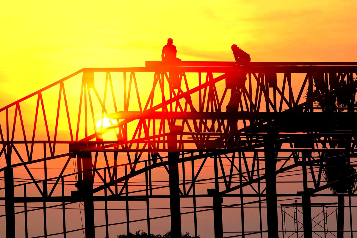 group of worker work late wilding steel structure in construction site on sun set abstract nature background