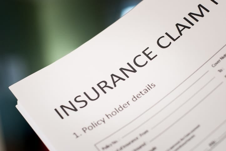 Close-up of an insurance claim form showing the title and policy holder details section on white paper